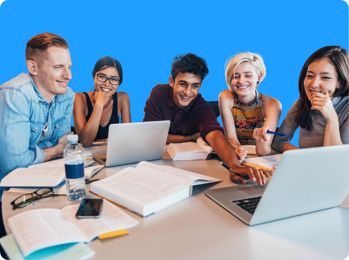 Students collaborating around a laptop with books and study materials during a group learning session.